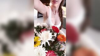 Braids swing as that babe leans forward holding flowers