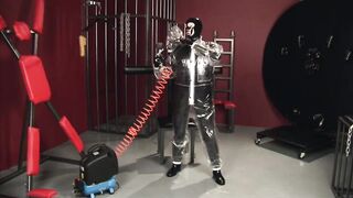 Golden-Haired gal in ebony latex catsuit full encased in inflatable rubber and full body plastic costume